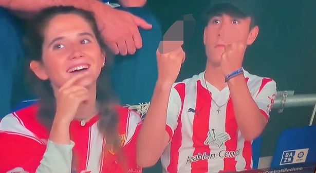 Moody football fan makes X-rated gesture at TV camera - and gets slap from girlfriend